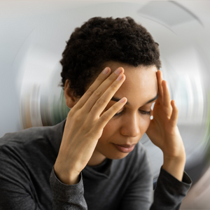 Woman holding her head due to experiencing BPPV symptoms.