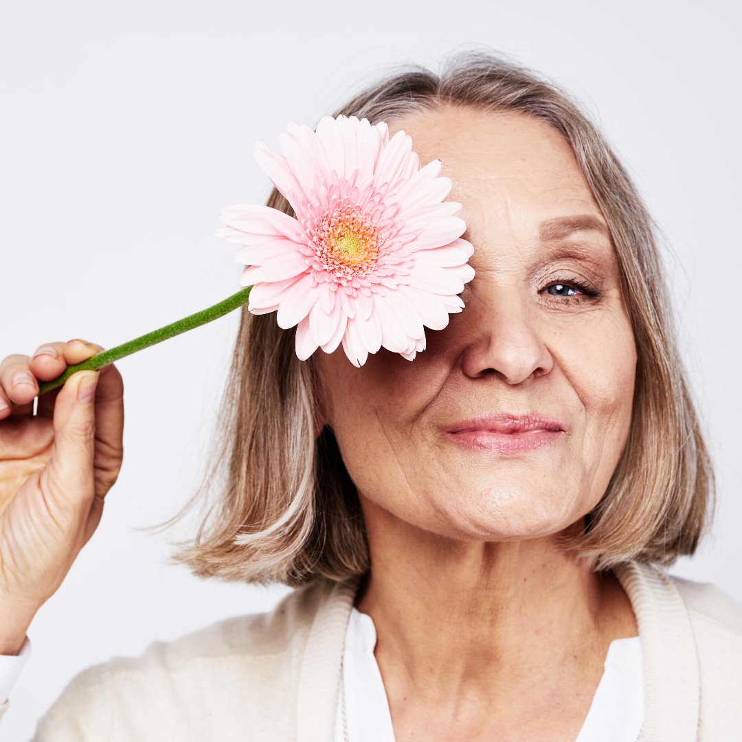 older woman holding a flower